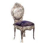 A silver pin cushion in the form of an elaborate chair, the blue velvet seat below a shaped back