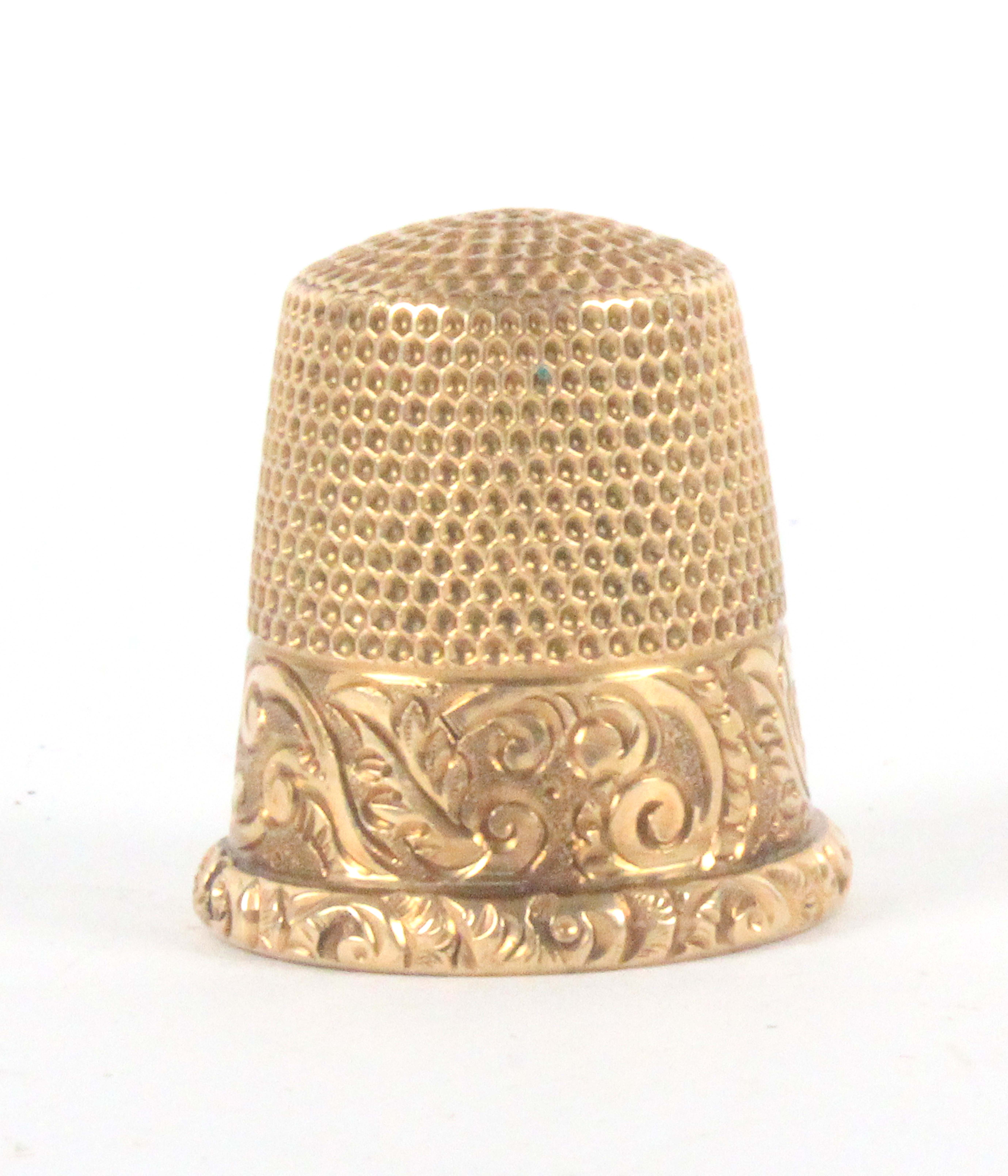 An American 14k gold thimble, by Ketcham and McDougall the scroll decorated frieze with vacant