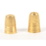 Two gold thimbles, comprising a French example with line and dot frieze to a vacant cartouche, the