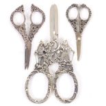Three pairs of silver scissors, comprising a Dutch pair with figural arms and scroll cast loops,