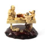 A late 19th Century Japanese sectional ivory figure group of a man and two children, fixed to an