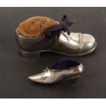 A silver shoe pin cushion and another, in soft metal, the first in the form of a lady's shoe with