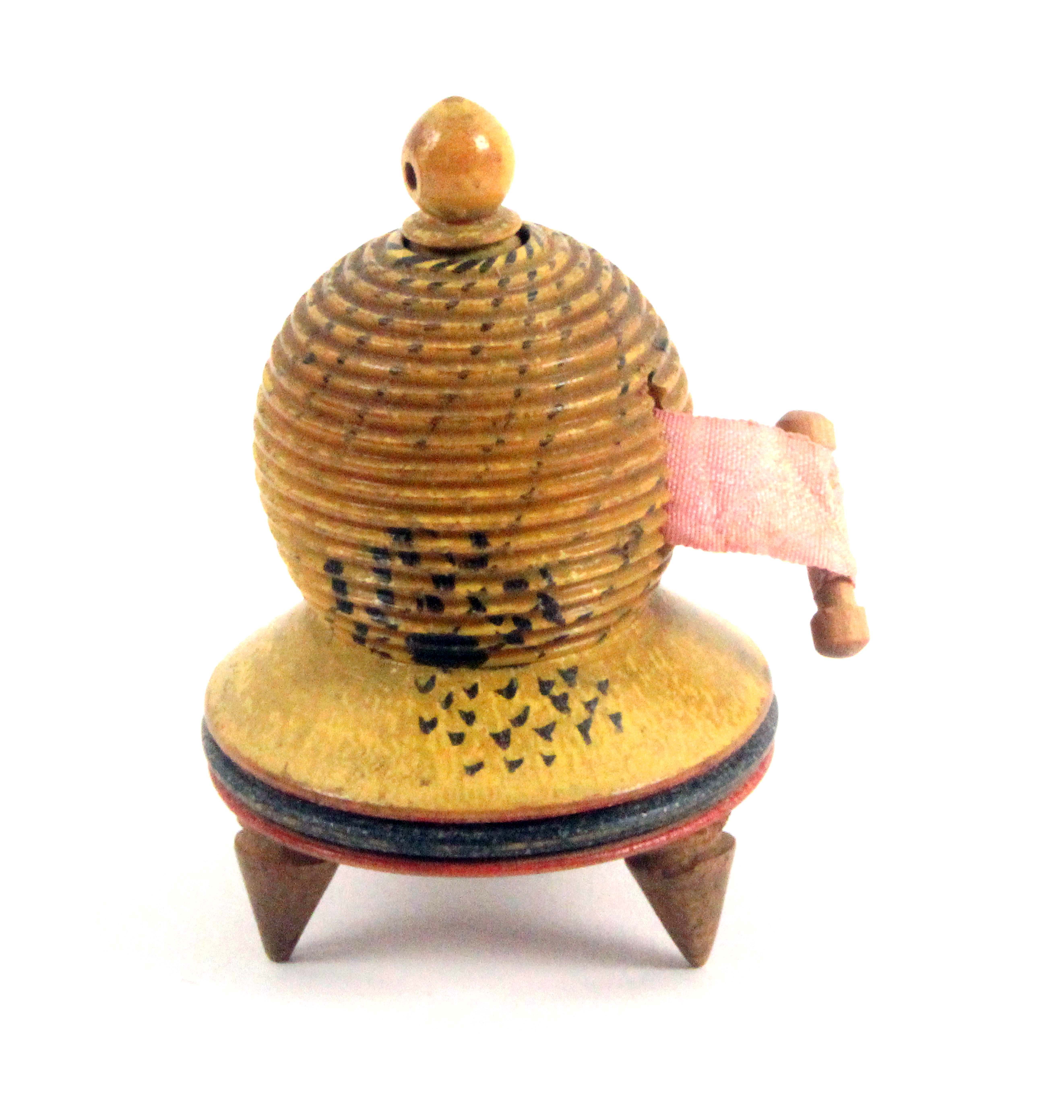 An early Tunbridge ware painted white wood tape measure in the form of a bee skep, repaired old tape