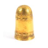 A gold thimble, of good gauge of narrow tall form with hand punched deep dome plain sides between