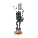 A 19th Century combination pin cushion and thimble stand, in the form of a grape picker in bronze, a