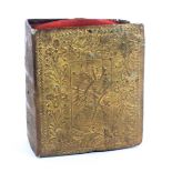 A gilt foil book form pin cushion, the covers with panels of musical and military trophies within