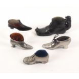 Five shoe form pin cushions, comprising a white metal example in the form of a lady's shoe