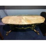 A long onyx coffee table, with ornate and heavy brass base