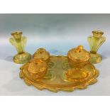 An amber coloured seven piece glass dressing table set