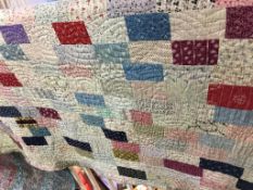 A Durham quilt decorated in patchwork, the reverse on a red ground decorated with flowers, 204 x