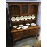 A small oak Arts and Crafts dresser, the top with leaded glass door, below a single door and two