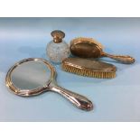A silver engine turned hand mirror, two silver backed brushes and a silver mounted scent bottle