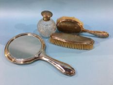 A silver engine turned hand mirror, two silver backed brushes and a silver mounted scent bottle
