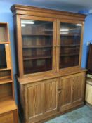 A large display cabinet with oak top, with glazed doors and adjustable shelves below a pine two door