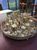 A large circular silver plated tray supported on claw feet and a selection of goblets