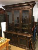 An Edwardian oak three door bookcase, with carved moulded cornice, three glazed doors with
