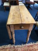An antique pine drop flap kitchen table, with single drawer, 122cm length