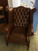 A button back brown leather wing armchair