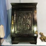 A carved oak hanging cabinet