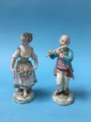 A pair of Derby figures of a lady holding a basket of flowers, with flowers in her hair and a