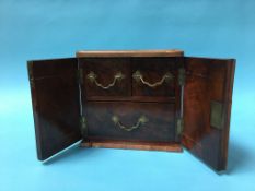 A small walnut two door cabinet, opening to reveal three drawers, 25cm wide