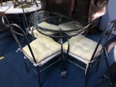 A glass circular kitchen table with four metalwork chairs