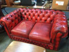 A red leather Chesterfield two seater sofa