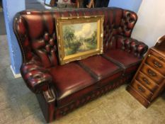 A maroon leather Chesterfield three seater sofa