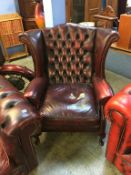 A leather oxblood wing back Chesterfield armchair