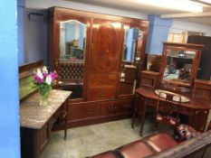 An Edwardian mahogany bedroom suite, comprising triple door wardrobe, mirror back dressing table and