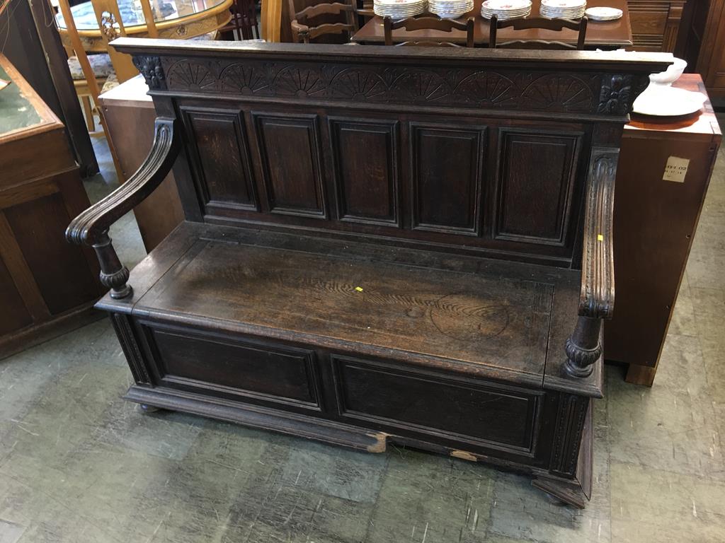 A large oak settle, with five panelled back and swept arms