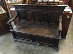 A large oak settle, with five panelled back and swept arms