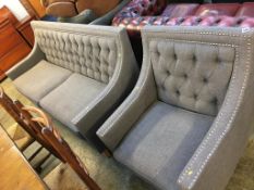 A grey button back and chrome studded settee and matching armchair