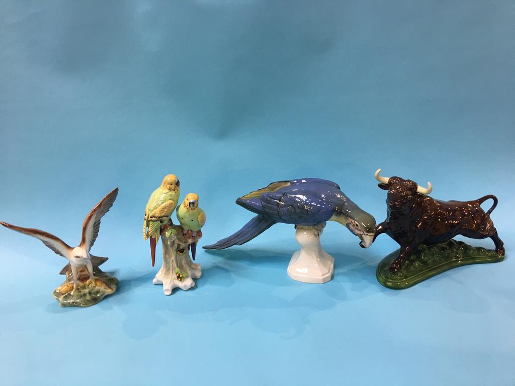 A Royal Dux model of a Macaw, two budgerigars on a stand and a model of a bull etc. (4)