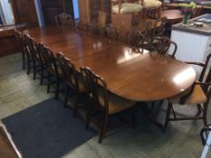 A reproduction mahogany triple pillar dining table, with three extra leaves and a set of 12