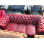 An oxblood Chesterfield three seater bed settee