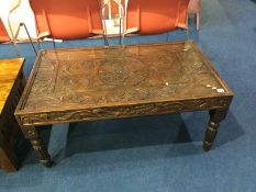 A heavily carved mahogany coffee table