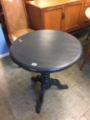 A painted circular tripod table