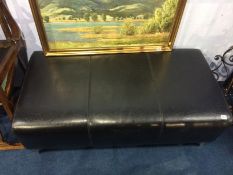 A large black leather foot stool