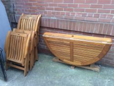 A teak garden table and four folding chairs