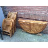 A teak garden table and four folding chairs