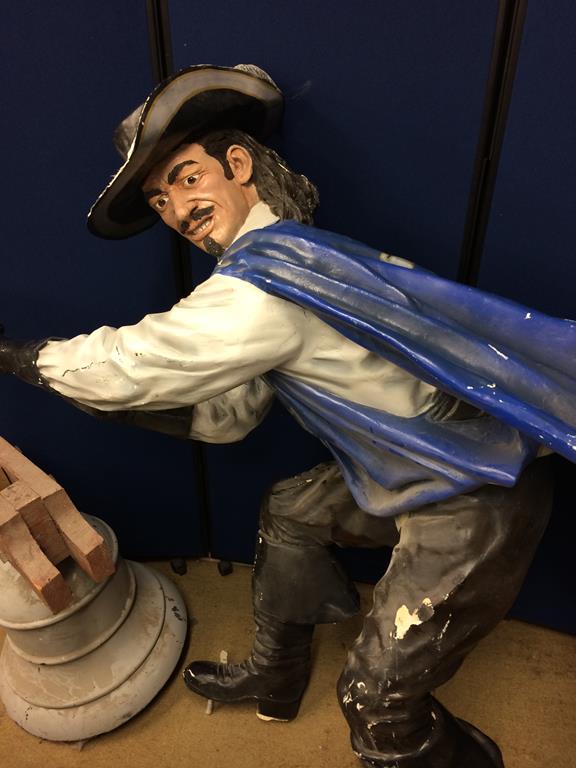 A Lifesize fibre glass figure of D'Artagnan scaling a wall, a prop bell and a prop milestone marker. - Image 2 of 4