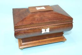 A small mahogany work box with fitted interior, waisted curving sides, supported on brass ball feet.
