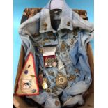 A denim jacket with numerous cap and shoulder badges and medals etc.
