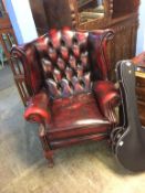 An oxblood Chesterfield high back wing armchair