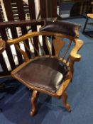 A 1930's oak swivel chair with inset leather seat and back