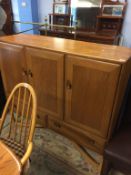 An unusual Ercol Golden Dawn, three door side cabinet, supported on shaped legs with cross frame