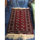 An Afghan rug, the madder red ground with two rows of geometric guls and main sunburst border and