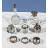 A silver topped perfume bottle, 2 silver pin jars, ink well, 3 napkin rings and one other inkwell