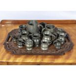 A carved wooden tray and an assortment of pewter measures